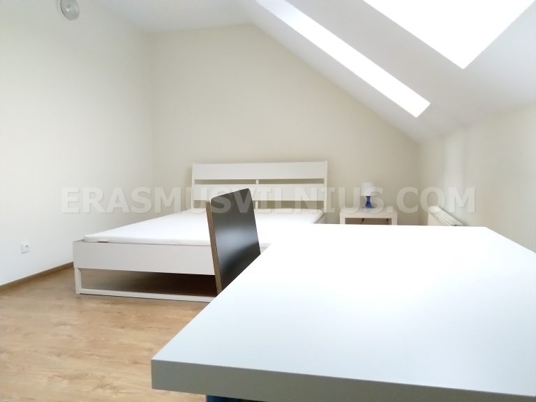 Room detail showing mirror and bedside area in renovated attic flat